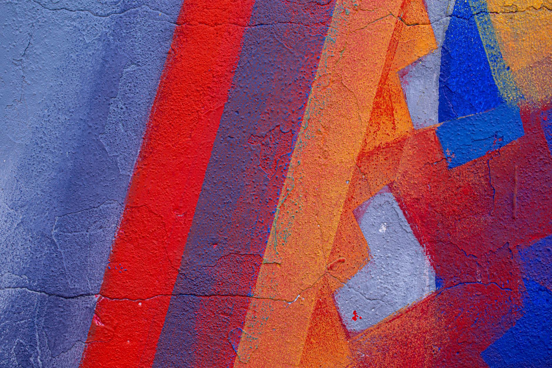 Close-up of a colorful abstract street art mural with vivid geometric patterns and textures.