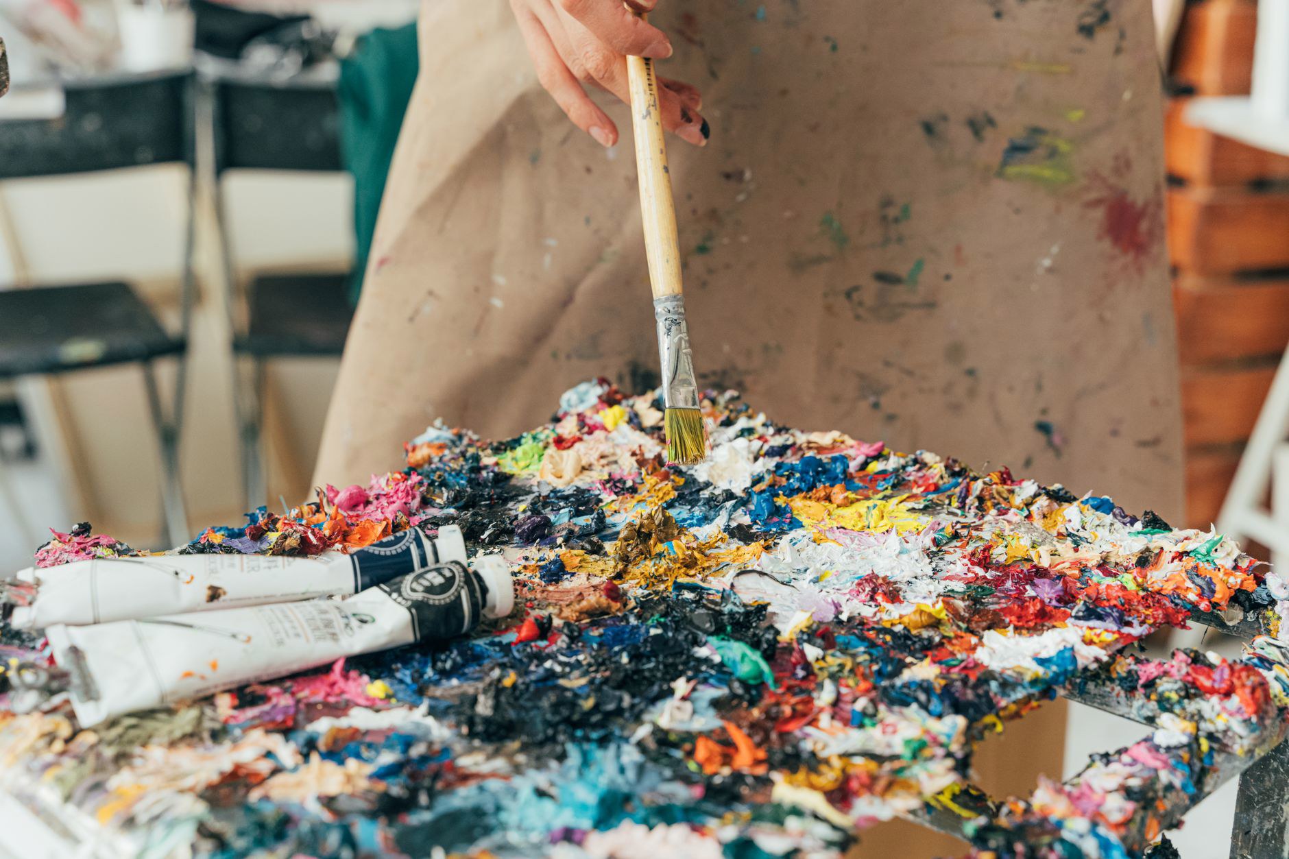 Vibrant paint palette with brush and tubes in an artist's studio setting.